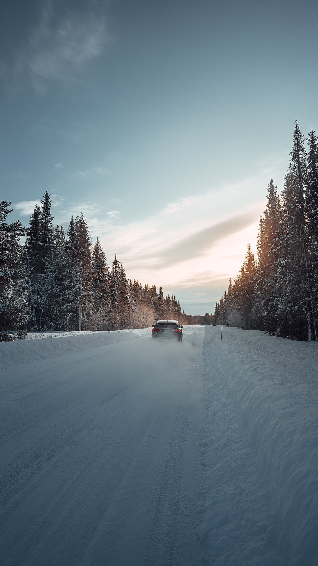 Auto auf einer verschneiten Straße durch den Winterwald